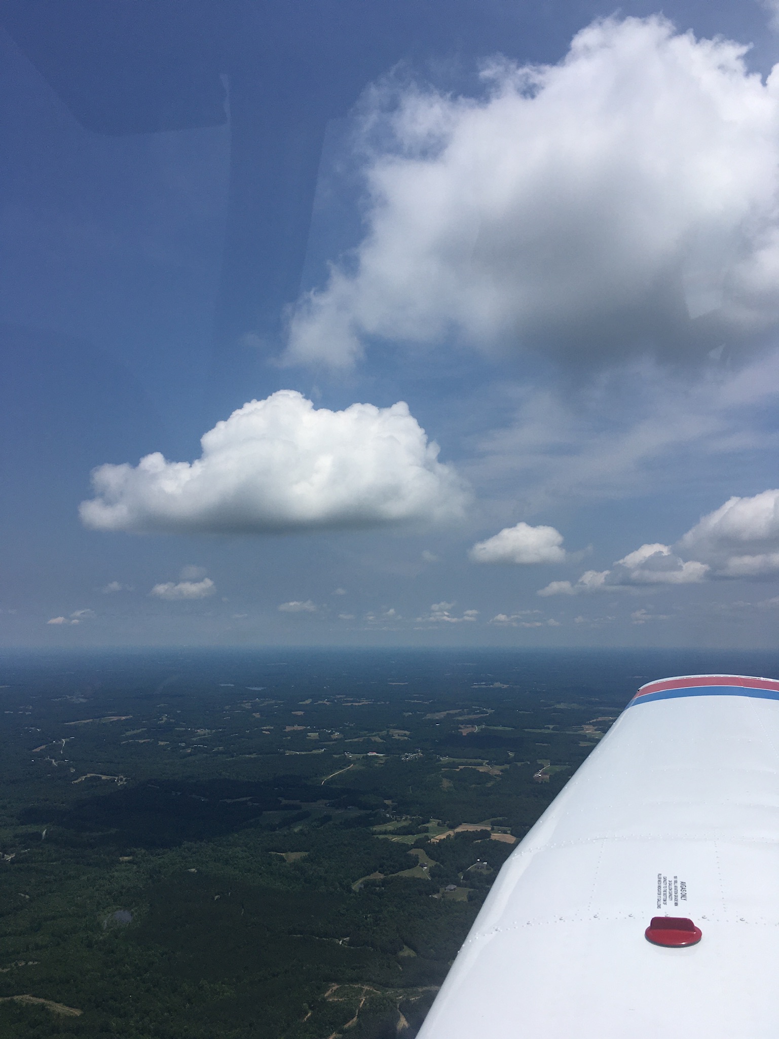 Clouds and the right wing of a Piper Warrior airplane