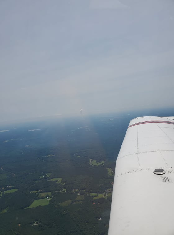 Looking out the right window, the sky is hazy, part of a wing can be seen
