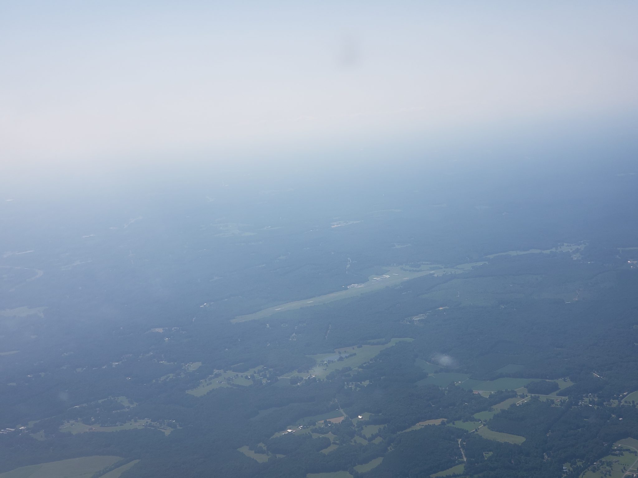 Hazy sky with a runway a couple miles away.