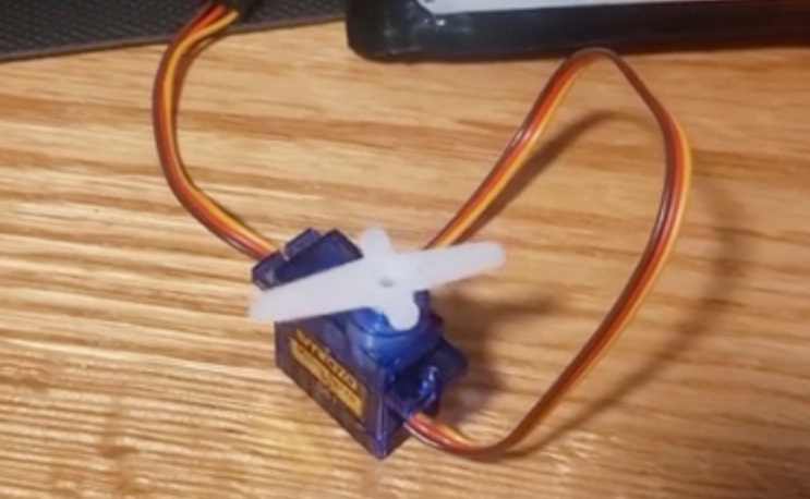 blue case servo with a white arm, cables running off screen. sitting on a desk.